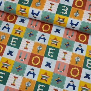 Könnte beinhalten: Ein farbenfroher Stoff mit einem Patchwork-Design mit Buchstaben, Sternen, Globen und Flugzeugmotiven. Die Quadrate sind in Blau-, Gelb-, Orange- und Rottönen gehalten und schaffen ein verspieltes und lehrreiches Thema.