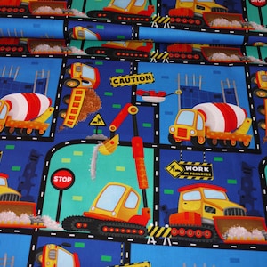 Könnte beinhalten: Ein blauer Stoff mit einem sich wiederholenden Muster von Baufahrzeugen. Die Fahrzeuge sind gelb, rot und schwarz. Der Stoff hat die Worte "Work in Progress" und "Caution" aufgedruckt.