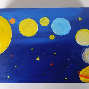 May include: A wooden box painted with a blue night sky and yellow, orange, and white planets. The box is decorated with small yellow stars and red and green dots.
