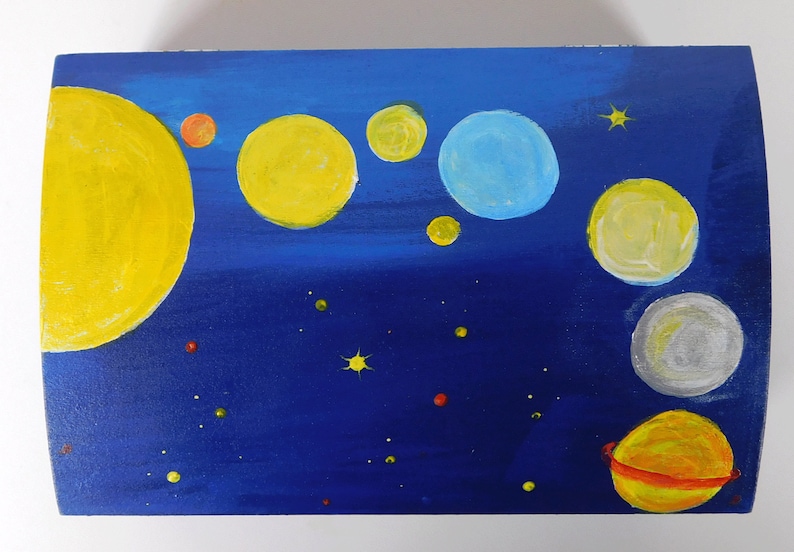 May include: A wooden box painted with a blue night sky and yellow, orange, and white planets. The box is decorated with small yellow stars and red and green dots.