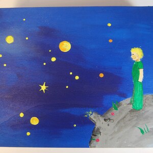 May include: A hand-painted wooden box with a blue night sky background. The box features a yellow star, a yellow crescent moon, and a small figure of a person standing on a grey rock. The figure is wearing a green shirt and trousers.