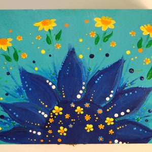 May include: A blue and yellow painted wooden box with a sunflower design. The sunflower has a blue centre with yellow petals and white dots. The background is turquoise with yellow flowers and orange dots.