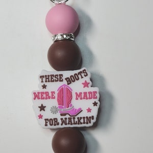May include: Pink and brown beaded keychain with a white charm that says "These Boots Were Made For Walkin'" with a pink cowboy boot graphic.