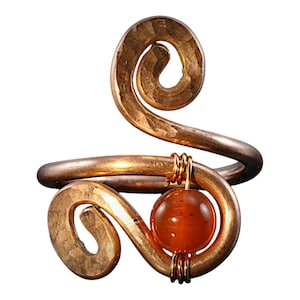 May include: A gold-toned ring with a swirling design and a single orange gemstone.