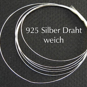 Op de afbeelding: Een bundel zacht, zilverkleurig draad, opgerold in een cirkelvorm. De tekst "925 Silber Draht weich" is in het wit gedrukt. De draad wordt waarschijnlijk gebruikt voor het maken van sieraden of knutselen.