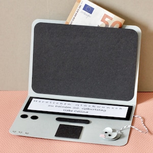 Könnte beinhalten: Eine hellgraue Grußkarte aus Karton in Laptop-Form mit einem schwarzen Bildschirmbereich, einer Tastatur mit schwarzen Filzakzenten und einem weißen Papierstreifen mit der Aufschrift "Herzlichen Glückwunsch zu Deinem 22. Geburtstag liebe Celina".