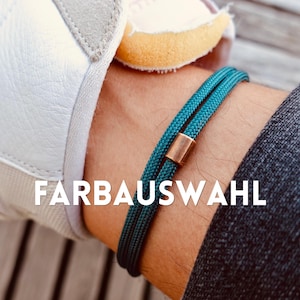 Könnte beinhalten: Türkisfarbenes Armband mit kupferfarbenem Verschluss. Das Armband besteht aus zwei parallelen Schnüren. Der Text "FARBAUSWAHL" wird in weißen Buchstaben am unteren Bildrand angezeigt.