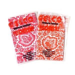 May include: Two red and white patterned plastic tablecloths with the text "Gelo Tischdecke" printed on them. The tablecloths are packaged in plastic.