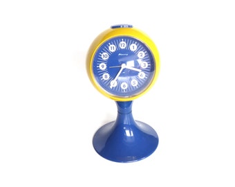 Horloge de table des années 70, réveil pied tulipe "Lève-toi !" Bénédiction jaune-bleu