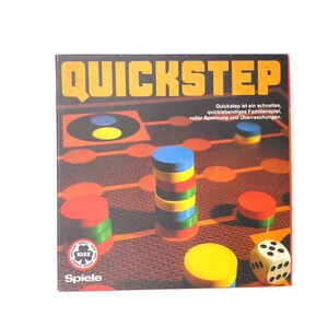 Könnte beinhalten: Eine Spielschachtel mit dem Titel "QUICKSTEP" in großen, fetten Buchstaben. Die Schachtel zeigt ein farbenfrohes Spielbrett mit roten, gelben, blauen und grünen Spielsteinen. Der Text auf der Schachtel lautet "Quickstep ist ein schnelles, spannendes Familienspiel voller Spannung und Überraschungen."