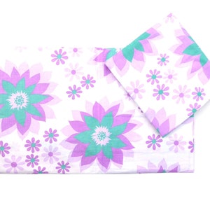Puede incluir: Un juego de dos piezas de ropa de cama blancas con un patrón floral. El patrón presenta flores grandes de color púrpura y verde con flores púrpuras más pequeñas dispersas por todas partes.