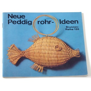 Puede incluir: Un folleto azul con el t&iacute;tulo "Neue Peddigrohr-Ideen" y el texto "Brunnen-Reihe 133". La portada presenta un pez de mimbre tejido con un anillo de alambre.