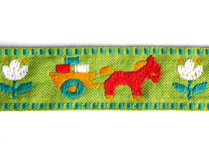 May include: Green ribbon with a repeating pattern of white flowers, a red horse pulling a yellow wagon with colorful blocks, and a turquoise border.