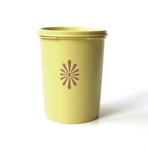 May include: A yellow plastic container with a brown flower design. The container has a lid.