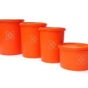 Può includere: Quattro contenitori arancioni in plastica per alimenti di varie dimensioni. Ogni contenitore ha un coperchio e un motivo floreale bianco. I contenitori sono disposti in ordine decrescente da sinistra a destra.