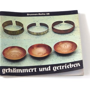 Puede incluir: Una portada de libro con el t&iacute;tulo "gehaemmert und getrieben" en texto negro sobre fondo blanco. La portada presenta seis im&aacute;genes de cuencos y pulseras de cobre.