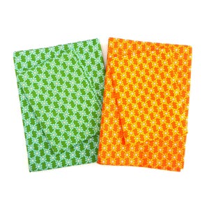 Puede incluir: Dos artículos de tela con estampados florales. Uno es verde con flores blancas y verde claro, y el otro es naranja con flores amarillas. Los artículos son rectangulares y parecen estar doblados o cerrados.
