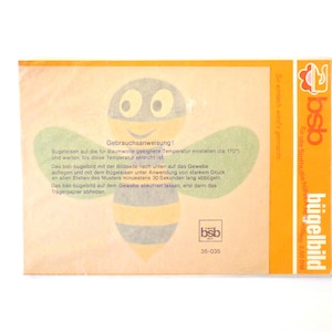 May include: A yellow and black bee iron-on transfer with instructions in German. The instructions say to set the iron to the cotton setting (about 170 degrees Celsius) and press for 30 seconds. The transfer is from the brand "bsb bügelbild".