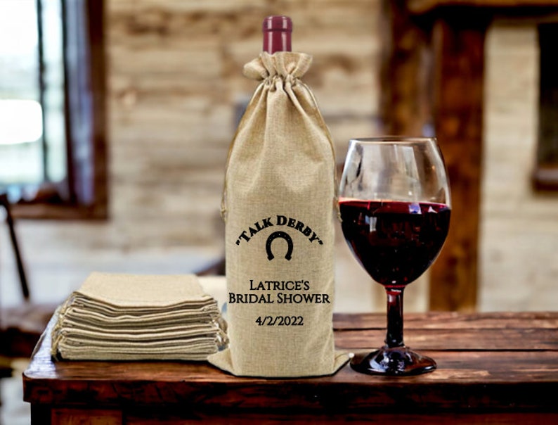 May include: A burlap wine bag with a horseshoe design and the text "Talk Derby" and "Latrice's Bridal Shower 4/2/2022".