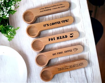 May include: Set of five wooden spoons with coffee-themed sayings. The sayings are: "A Day Without Coffee is Like... Just Kidding. I Have No Idea!" "It's Cawfee Time!" "Pot Head" "But First... Coffee" "I Dwin On Coffle Cumbs And Cliss Wodds"
