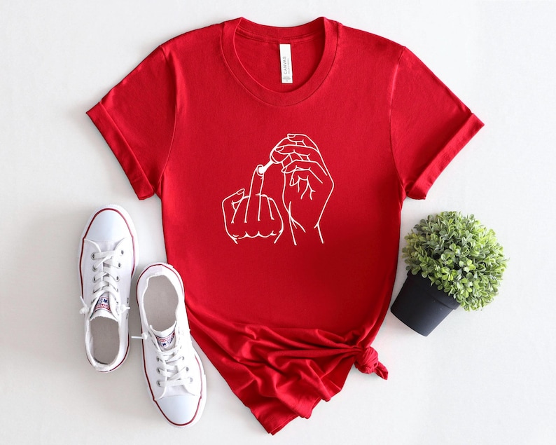 May include: Red short-sleeved t-shirt with a white line drawing of two hands making a rude gesture.