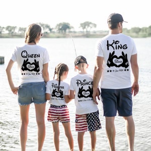 Könnte beinhalten: Eine vierköpfige Familie trägt weiße T-Shirts mit schwarzem Text und Mickey-Mouse-Handdesigns. Die Shirts sagen "King", "Queen", "Princess" und "Prince" mit dem Datum, seit dem sie "Since" sind.