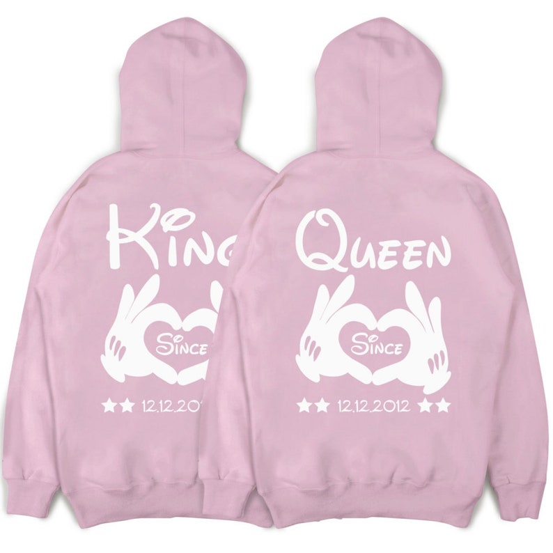 May include: Two pink hoodies with white text and graphics. One hoodie says "King" with a heart and "Since 12.12.20" and the other says "Queen" with a heart and "Since 12.12.2012".