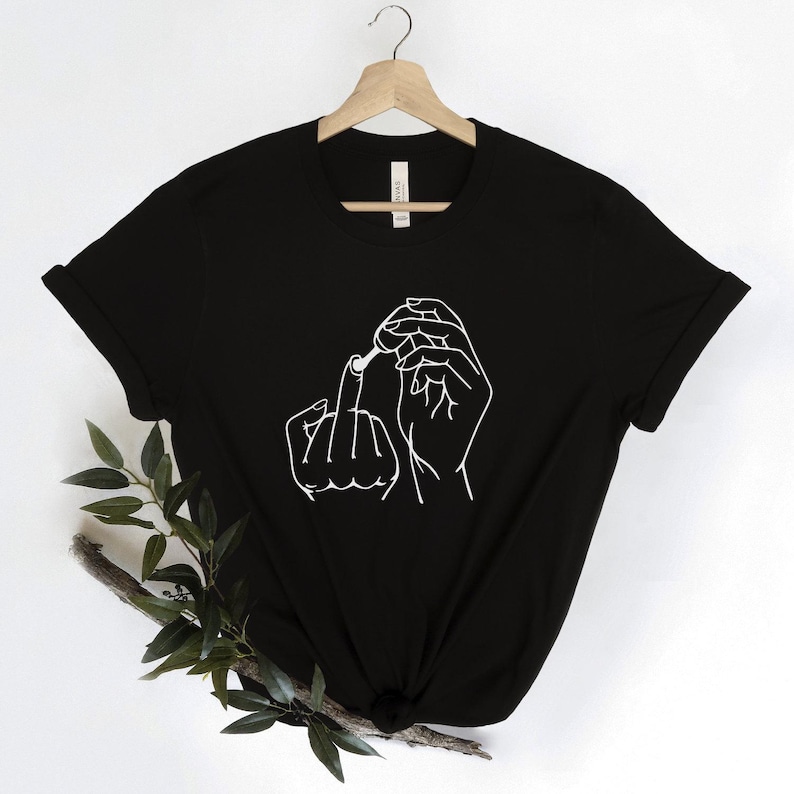 May include: Black t-shirt with a white line drawing of a hand holding a cigarette and giving the middle finger.