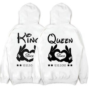 May include: White hooded sweatshirts with black text and graphics. One sweatshirt says "King" with a Mickey Mouse hand heart graphic and "Since 12.12.20". The other sweatshirt says "Queen" with a Mickey Mouse hand heart graphic and "Since 12.12.2012".