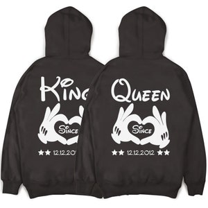 May include: Two black hooded sweatshirts with white text and graphics. One sweatshirt says "King" with a heart and the text "Since 12.12.20". The other sweatshirt says "Queen" with a heart and the text "Since 12.12.2012".