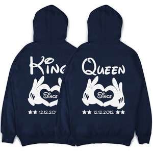 May include: Two navy blue hoodies with white text and graphics. The hoodie on the left says "King" with a heart and the text "Since 12.12.2012". The hoodie on the right says "Queen" with a heart and the text "Since 12.12.2012".