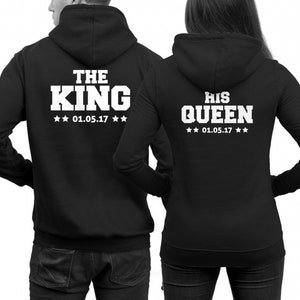 Puede incluir: Dos sudaderas con capucha negras con texto blanco en la espalda. Una sudadera dice "The King" con la fecha "01.05.17" y la otra dice "His Queen" con la misma fecha.