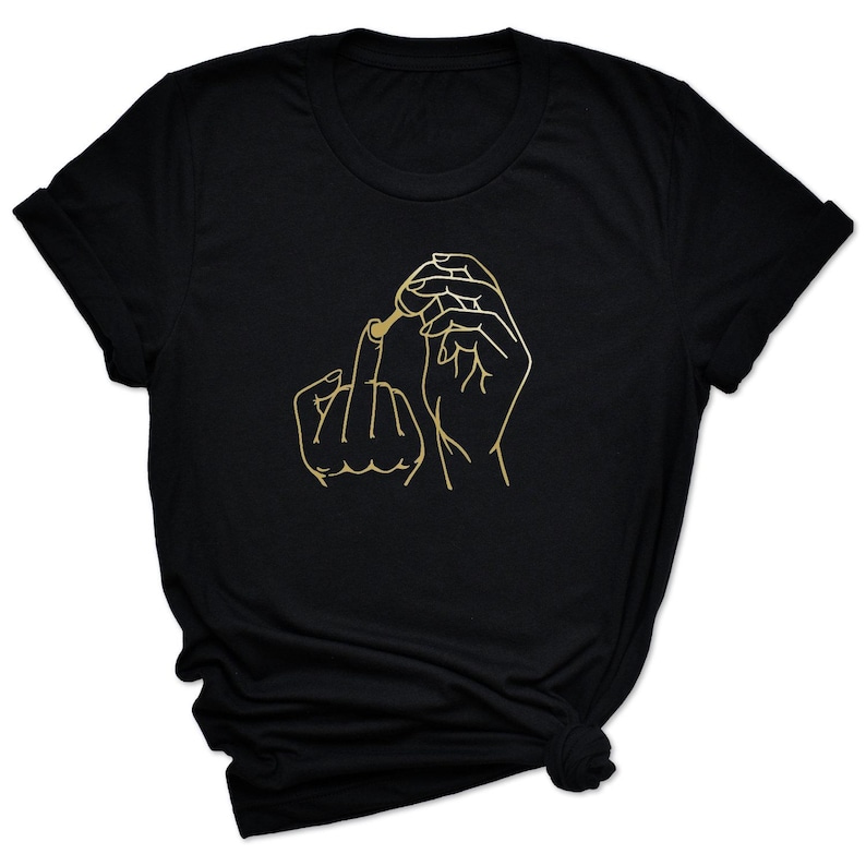 May include: Black t-shirt with a gold outline of a hand giving the middle finger and applying nail polish.