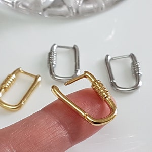 May include: Three pairs of hoop earrings, one pair is gold, one pair is silver, and one pair is gold with a textured design.