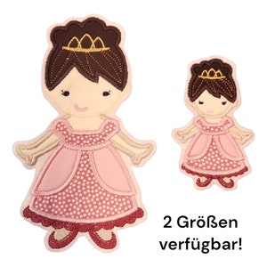 Könnte beinhalten: Zwei gestickte Bügelbilder einer Prinzessin in einem rosa Kleid mit weißen Punkten. Das größere Bügelbild ist etwa 10 cm hoch und das kleinere etwa 5 cm hoch. Der Text "2 Größen verfügbar!" befindet sich unter den Bügelbildern.