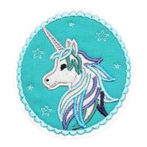 Könnte beinhalten: Ein gestickter Patch in Türkisblau mit einem weißen Einhorn mit blauem und grünem Mähne und Schweif. Das Einhorn ist von weißen Sternen umgeben.
