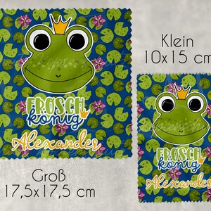 Könnte beinhalten: Ein blauer Stoff mit einem grünen Frosch, der eine goldene Krone trägt und den Text "Frosch könig Alexander". Der Stoff ist in zwei Größen erhältlich: 10x15 cm und 17,5x17,5 cm.