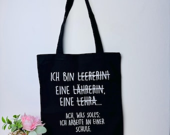 May include: Black tote bag with white text that reads "ICH BIN LEERERIN! EINE LÄHRERIN, EINE LEHRA... ACH, WAS SOLL'S: ICH ARBEITE AN EINER SCHULE."