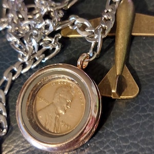 Coin necklace on 23 inch steel chain. 1944 copper penny in rose gold tone locket with bronze airplane charm