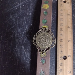 Leather watchband style bracelet with antique bronze watch front. Leather is hand stamped and painted with buckle