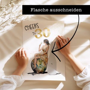 May include: A white card with the words "Cheers to 30" in black and gold lettering. A woman in a gold dress is sitting on a globe, holding a glass of champagne. The card is being held by a hand, and a bottle of champagne is being cut out of the card.