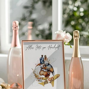 May include: A gold-framed picture with a watercolor illustration of a couple sitting on a globe with a plane flying above them. The text on the picture reads "Alles Gute zur Hochzeit" and "Die sch&ouml;nste Reise beginnt zu zweit".