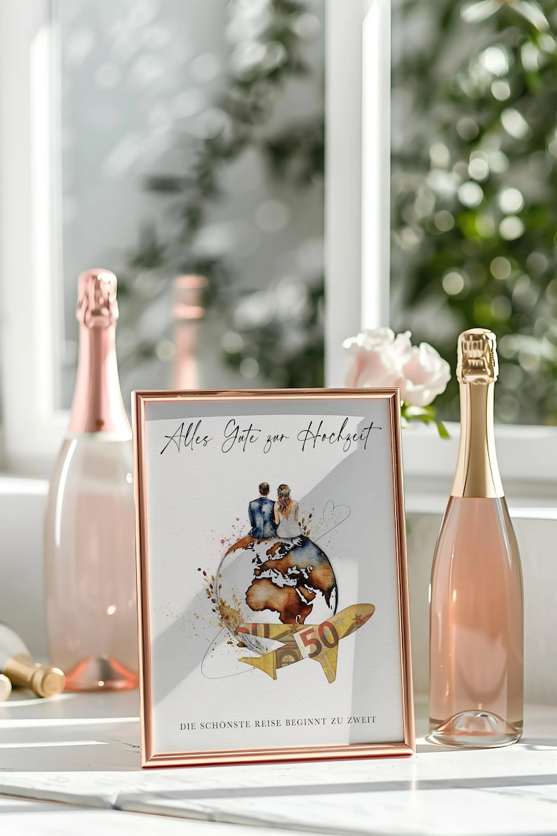May include: A gold-framed picture with a watercolor illustration of a couple sitting on a globe with a plane flying above them. The text on the picture reads "Alles Gute zur Hochzeit" and "Die sch&ouml;nste Reise beginnt zu zweit".