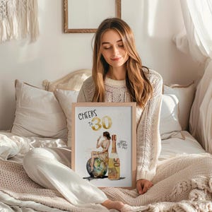 May include: A framed print with a watercolor illustration of a woman sitting on a globe, holding a glass of champagne. The woman is made of money bills. The print says "Cheers to 30" and "Happy Birthday to You".