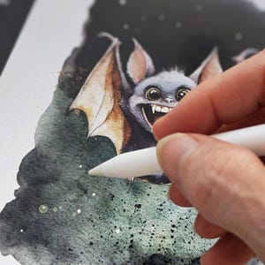 May include: A digital illustration of a cartoon bat with large eyes and a toothy grin. The bat is drawn in a watercolor style with a dark green and black background. The artist is using a stylus to add details to the illustration.