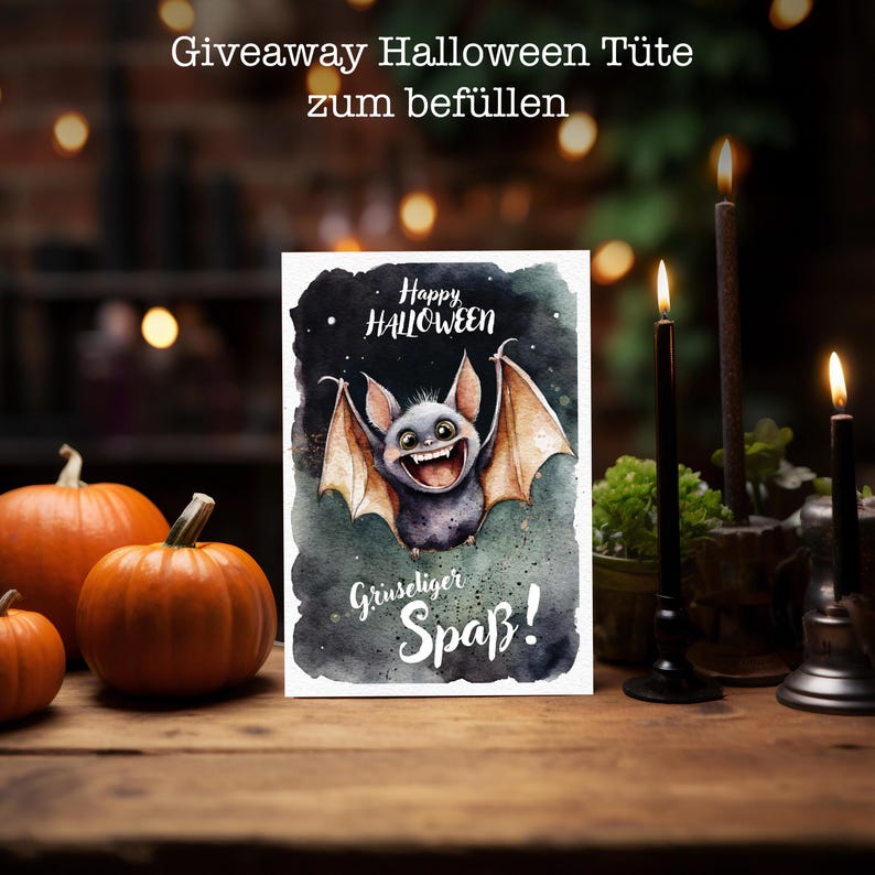 May include: A white card with a watercolor illustration of a smiling bat with outstretched wings. The bat is against a dark green and black background with stars. The text "Happy Halloween" is above the bat and "Gruseliger Spa&szlig;!" is below the bat.