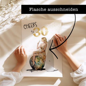 May include: A white card with the text "CHEERS TO 30" in black and gold lettering. A watercolor illustration of a woman sitting on a globe, holding a glass of champagne. The text "Flasche ausschneiden" is written in black on a white background.