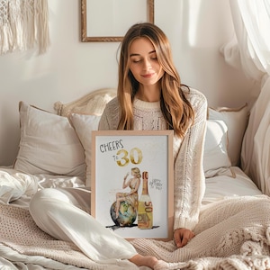 May include: A framed print with a watercolor illustration of a woman sitting on a globe, holding a glass of champagne. The bottle of champagne is made of money. The text on the print reads "Cheers to 30" and "Happy Birthday to You".