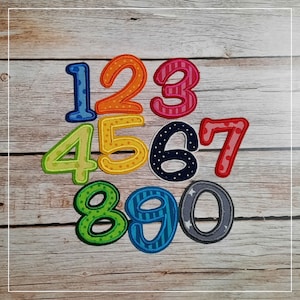 Könnte beinhalten: Zehn bunte Filz-Zahlen von 1 bis 10 mit verschiedenen Mustern und Designs. Jede Zahl ist in einer kontrastierenden Farbe umrandet.