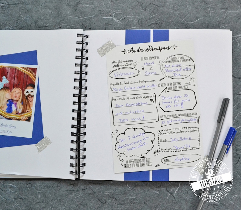 May include: A white page with black text and drawings. The text includes "An das Brautpaar" and "Vertrauen". There are two silver glitter stickers on the page.
